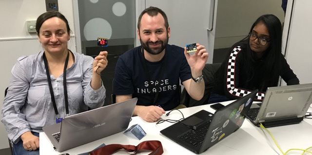 picture of three adults, two are holding small circuit boards